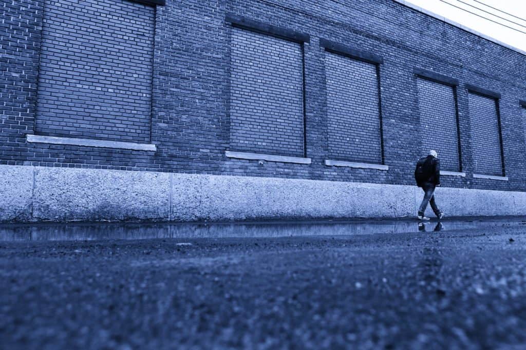 man walking in front of blue warehouse