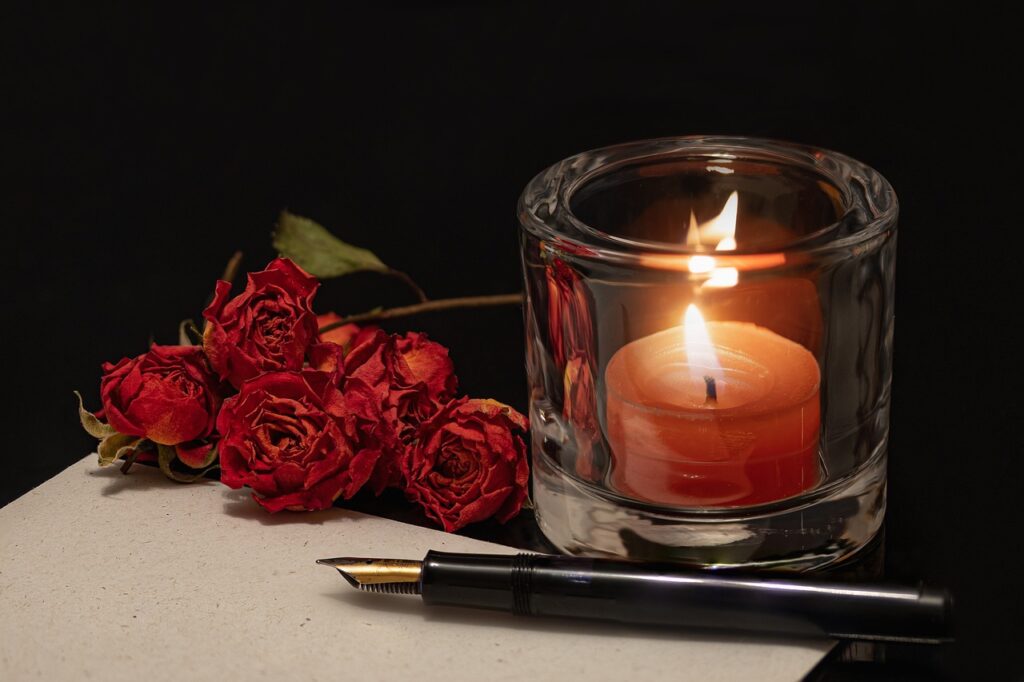 A candle, pen, paper, and a rose, representing the ritual of proprioceptive writing.